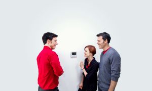 technician showing homeowners how to set the thermostat